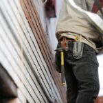 Close-up of a construction worker with hammer and tools, focused on the job.