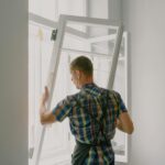 A professional installer fitting a modern window in a well-lit home interior.
